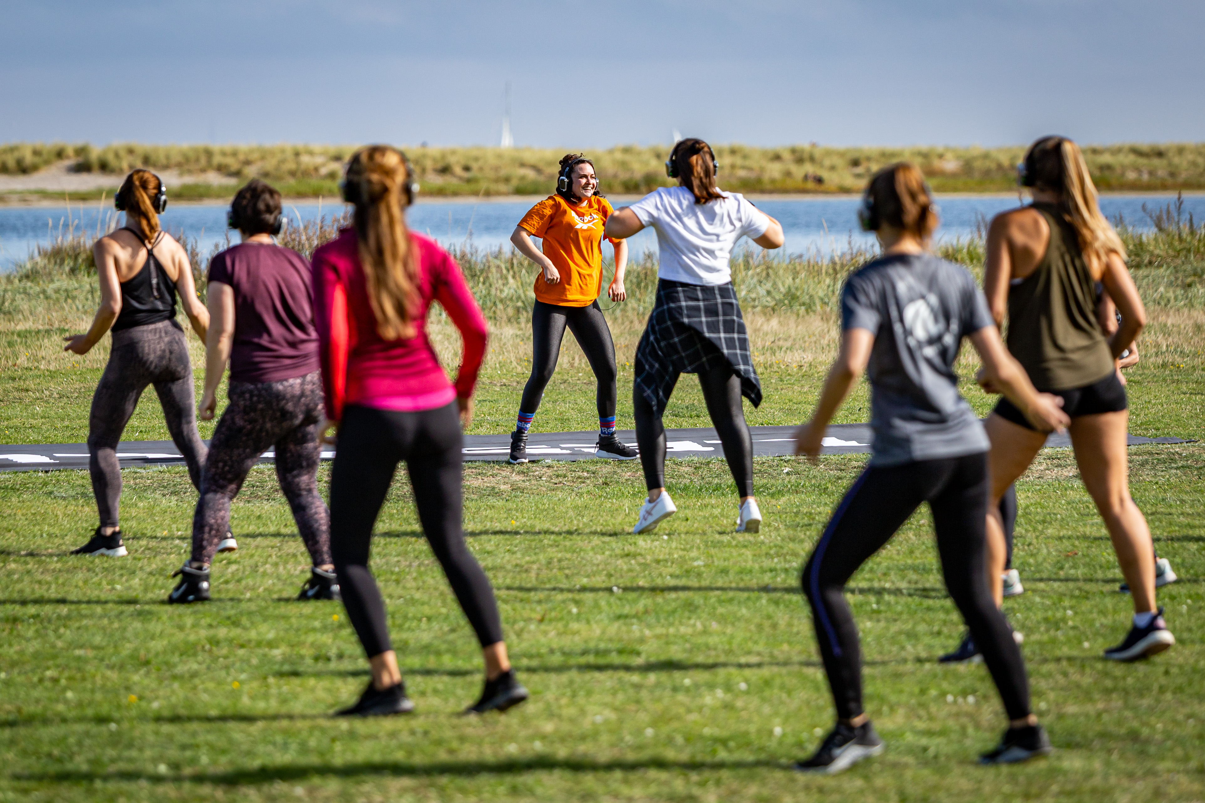 En flok mennesker danser ude i naturen med høretelefoner på, foto Silent FIT.jpg