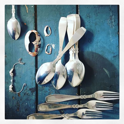Gamle sølvskeer og -gafler der ligger på et blåt bord, foto Lise Löfkvist Radl