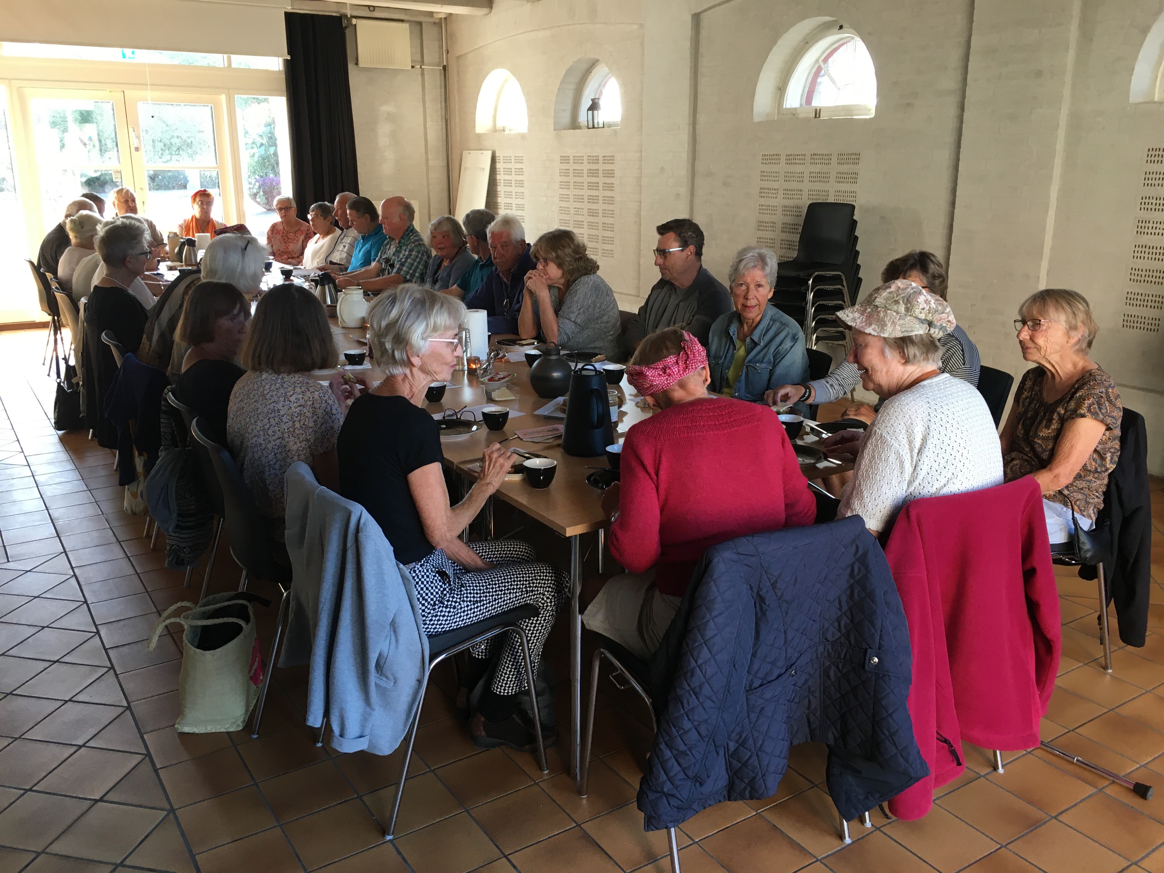 Pensionister samlet ved langbord i Rejsestaldens Vognport, foto Camilla Hultén.jpg